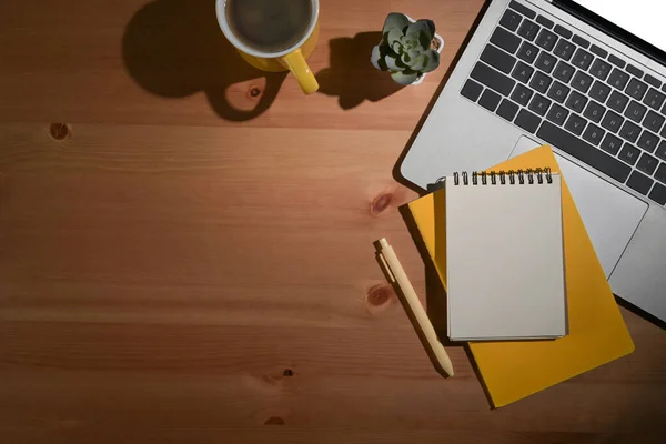 Houten tafel met computer laptop, koffiebeker en notebook. Bovenaanzicht, kopieer ruimte. — Stockfoto