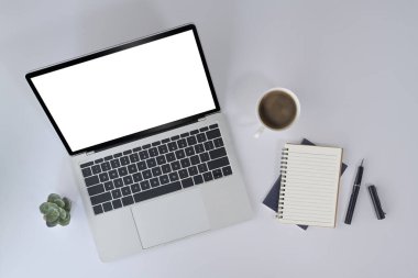 Dizüstü bilgisayar, defter ve kahve fincanı beyaz ofis masasında. Üst görünüm.