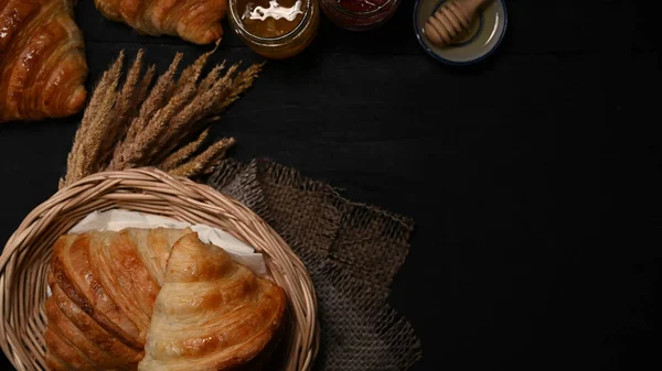 新鮮なバックアップされたクロワッサンでウィカーバスケットと蜂蜜とジャムの朝食 — ストック写真