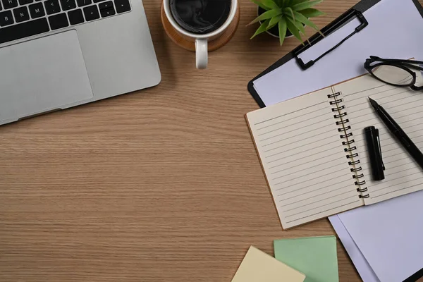 Dizüstü bilgisayar, kahve fincanı, defter, bardaklar ve saksı bitkisi..