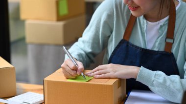 Karton kutunun üzerine yazı yazan kadın satıcı teslimat için paket ürün hazırlıyor. Çevrimiçi satış, e-ticaret kavramı.