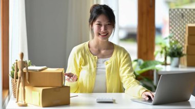 Genç işletme sahibi online müşteri siparişini kontrol etmek için bilgisayar laptopu kullanıyor.