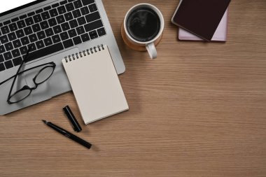 Masanın üstünde dizüstü bilgisayar, bardaklar ve kahve fincanı..