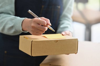 Karton kutuya adres yazan kadın çevrimiçi satıcıyı kapat. Çevrimiçi satış, e-ticaret kavramı.