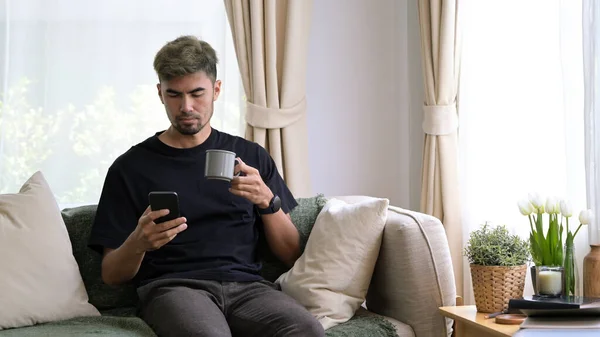 Jovem Sentado Sofá Confortável Usando Telefone Inteligente Desfrutando Lazer Fim — Fotografia de Stock