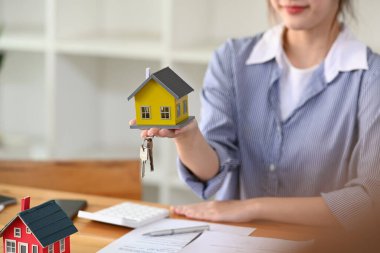 Finansal danışman ya da emlakçı ev modelinin elini tutuyor. Sigorta ve emlak konsepti.