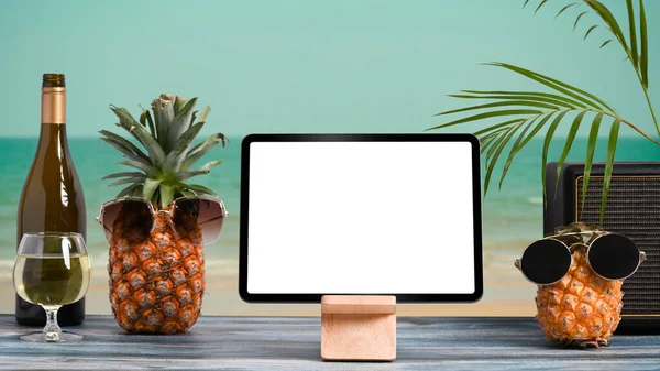 Mockup digital tablet and summer drinks on wooden table with tropical beach in background. Summer holiday concept.