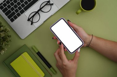 Genel bakış açısıyla genç bayan yaratıcı iş yerinde oturuyor ve akıllı telefon kullanıyor..