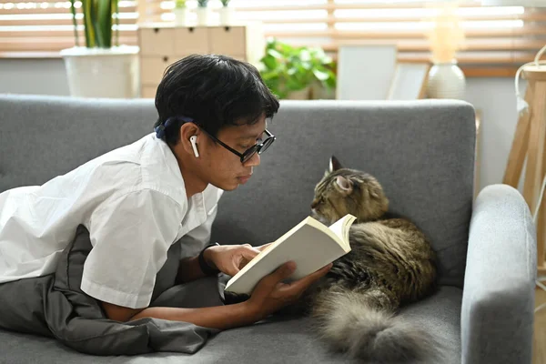 Случайный Человек Лежит Диване Своей Милой Кошкой Читает Книгу — стоковое фото