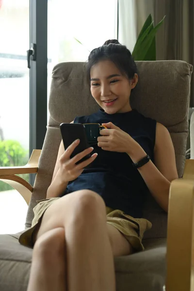 커피를 마시며 미디어를 스마트폰으로 확인하는 여성의 — 스톡 사진