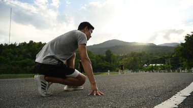 Genç sporcu başlangıç pozisyonunda, sabah dışarı koşmaya hazır. Sağlık ve spor konsepti.