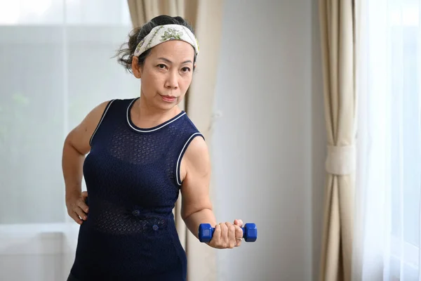 Sportif Orta Yaşlı Kadın Oturma Odasında Dambıllarıyla Egzersiz Yapıyor Emeklilik — Stok fotoğraf