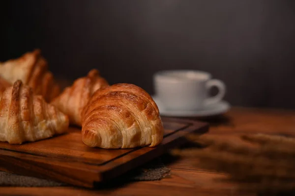 朝食のためのホットコーヒーと黒の木製のテーブルの上においしいバタークロワッサンを閉じます — ストック写真