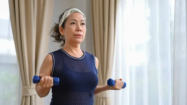 Aktif Orta Yaşlı Kadın Oturma Odasında Dambıllarıyla Egzersiz Yapıyor Emeklilik — Stok fotoğraf