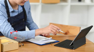 Genç erkek çevrimiçi satıcı dijital tablette ürün satın alma siparişini kontrol ediyor. E-ticaret, çevrimiçi iş, çevrimiçi satış kavramı.