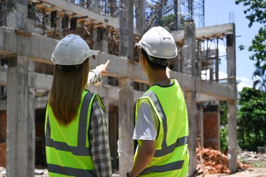 İnşaat alanında birlikte inşaat sürecini tartışan sarı yelekli mühendis takımı..