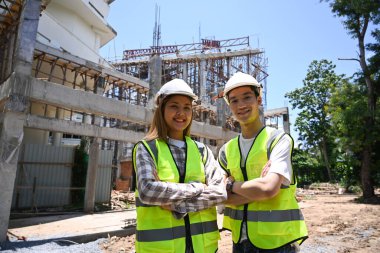 İnşaat alanında duran sarı yelekli ve kasklı iki mimar..