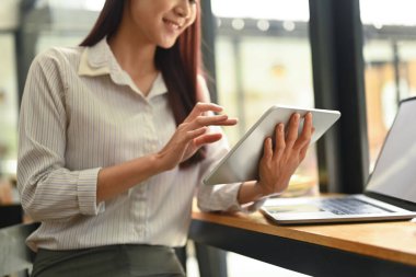 Modern ofiste tezgahta otururken dijital tablet kullanan güzel Asyalı kadın çalışanlar..