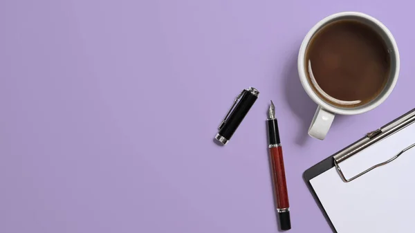 Top view cup of coffee, pen and blank clipboard on purple background with copy space.