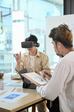 Web sitesi geliştirme ekibi sanal gerçeklik kulaklığını test ediyor, gelişmiş gerçeklik gelişimi üzerine beyin fırtınası yapıyor, gelecekteki iş teknolojileri üzerine çalışıyor..