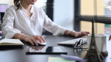 Genç girişimci parlak bir ofiste oturuyor ve modern cihazlar kullanıyor.. 