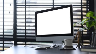 Bilgisayarlı ofis masası, kahve fincanı, paketler ve ev bitkisi. Reklam metniniz için boş ekran.