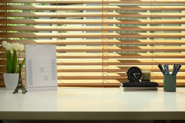 Çiçek saksısı, aroma mumu, kitaplar ve takvime sahip kadınsı bir iş yeri..