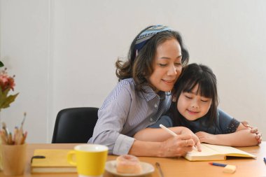 Yetişkin bir büyükannenin küçük torununa ev ödevi yapmasına yardım etmesi. Çok nesilli, aile ve aşk kavramı.