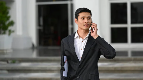 Jóképű Ázsiai Üzletember Sétál Modern Irodaház Előtt Beszél Üzlettársával Mobiltelefonon — Stock Fotó