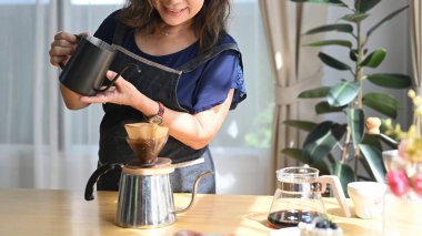 Gülümseyen emekli kadın kahvaltı için kahve hazırlıyor, sabahları evde boş vakit geçiriyor..