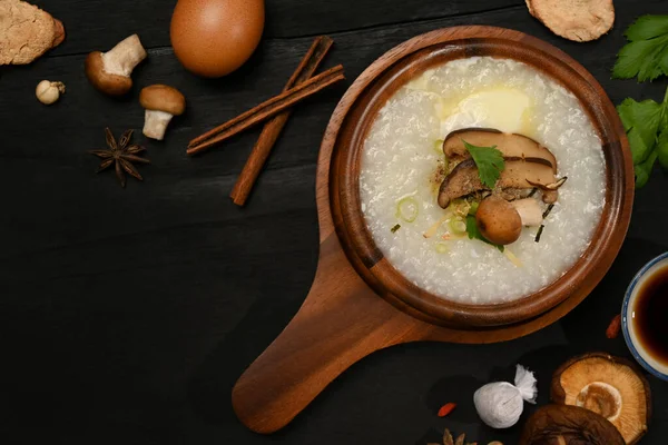 传统的中国米粥 配上煮得软的鸡蛋 姜片和葱片 放在黑色木桌上 以达到早餐的健康 — 图库照片