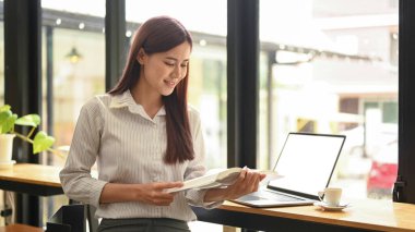 Rahat bir iş yerinde oturup kitap okuyan mutlu kadın serbest yazar..