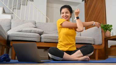 Neşeli kadın sabah antrenmanından önce kolunu esnetip ısınıyor..