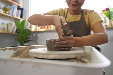 Önlüklü kadın atölyedeki çömlek çarkında el işi çanak çömlek yapıyor. Etkinlik, el işi, hobi kavramı.
