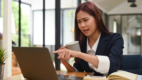 Upset young female office worker having problems with laptop, solving business problem.