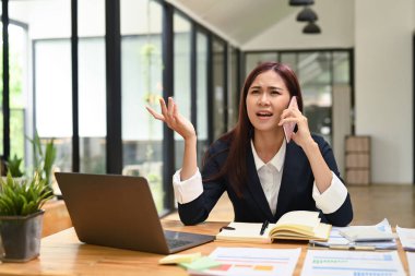 Ciddi kadın girişimci cep telefonuyla ciddi bir konuşma yapıyor, müşteriyle tartışıyor ya da iş sorununu çözüyor.