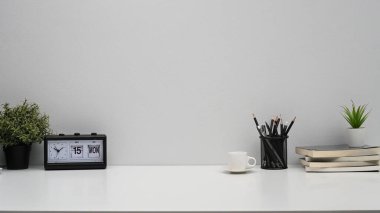 Çalar saati, kitapları, kahve fincanı ve kalem tutacağı olan ofis masası. Reklam metnin için hızını kopyala.