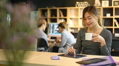 Yazılım mühendisleri dijital tablet kullanan takım lideri ve arka planda çalışan genç bilişim geliştirme ekibi.