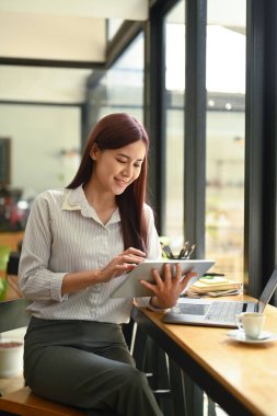 Çevrimiçi bilgileri ya da dijital tabletindeki e-postayı kontrol eden çekici kadın serbest yazar.