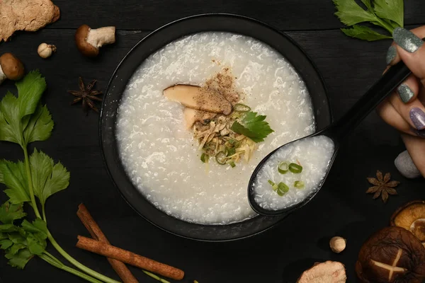 传统的中国米粥配上蘑菇 姜片和葱片 放在黑色木桌上享用健康早餐 — 图库照片