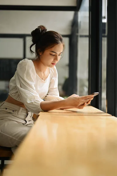 Charming Young Woman Sitting Window Coffee Shop Messaging Her Smartphone — 스톡 사진