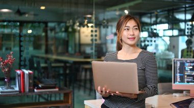 Modern işyerinde dururken dizüstü bilgisayar kullanan genç profesyoneller web geliştirici kodlayıcı.