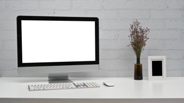 Beyaz ekranlı, tuğla duvara dayalı bir bilgisayar. Merkez ofis masası.