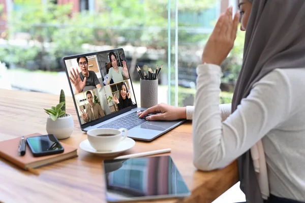 Young Muslim woman in hijab communicating by video conference on laptop computer.