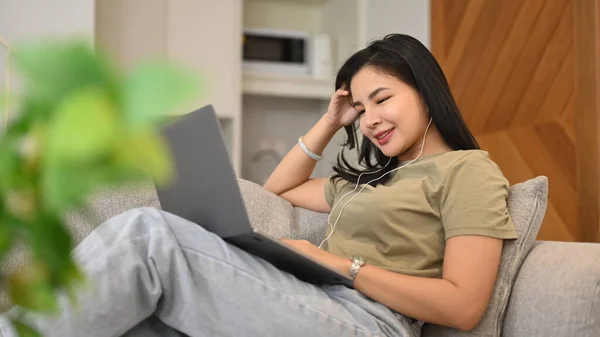 아시아 프리랜서가 인터넷으로 일하며 거실에서 휴식을 취하는 노트북으로 인터넷 서핑을 — 스톡 사진