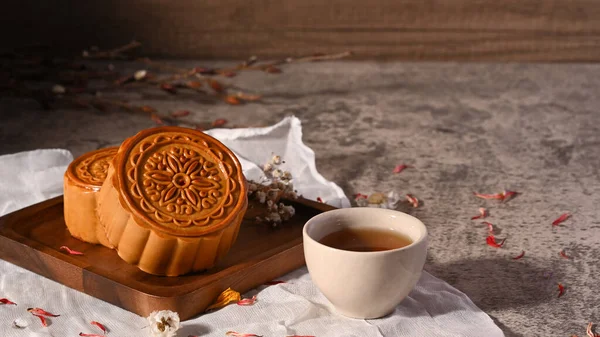 Mid autumn festival mooncake and and green tea on stone table.