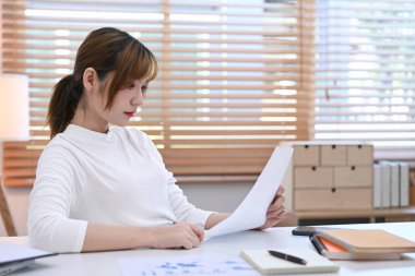 Konsantre genç yatırımcı istatistik belgesini okuyor, iç işlerinde iş stratejisi planlıyor.