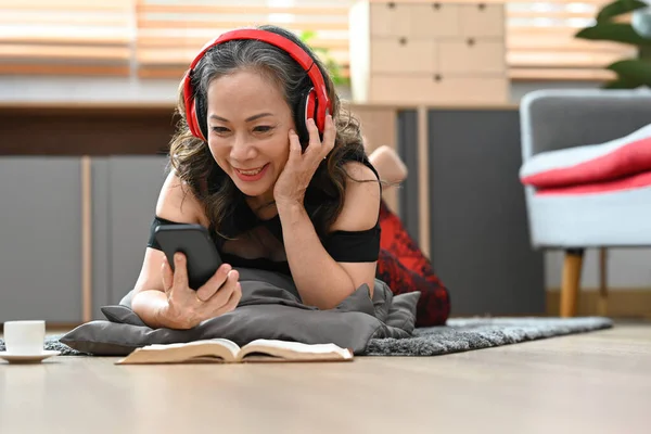 Smiling Mature Woman Wearing Wireless Headphone Using Smartphone Cozy Living — 스톡 사진