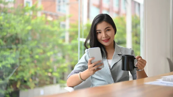 Stylish Young Businesswoman Holding Cup Coffee Using Mobile Phone — Stock Photo, Image