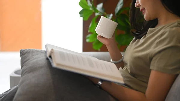 Calm Asian Woman Drinking Hot Tea Reading Book Comfortable Couch — Foto de Stock